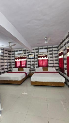 two beds in a large room with red accents at Vidhilekh hotel in Dwarka