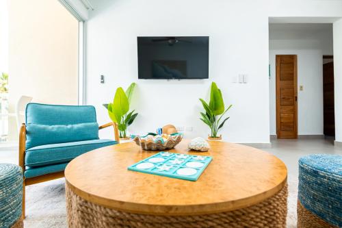 a living room with a table and a blue chair at Beachside 2BR- Steps From The Beach and City Center in Las Terrenas