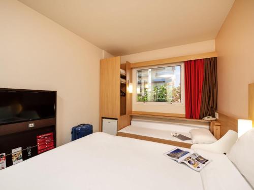 a hotel room with a bed and a window at Ibis São Carlos in São Carlos