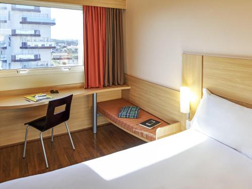 a bedroom with a bed and a desk and a chair at Ibis São Carlos in São Carlos