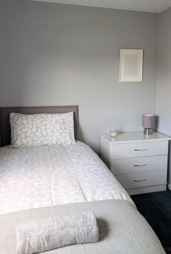 a bedroom with a bed and a white dresser and a drawer at Kintyre House in Campbeltown