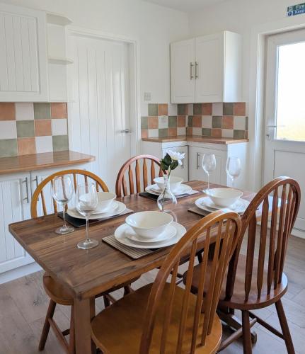 a kitchen with a wooden table with chairs and wine glasses at Kintyre House in Campbeltown