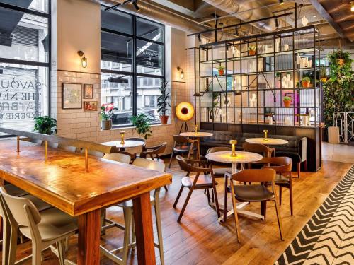 a restaurant with tables and chairs and windows at Novotel London Bridge in London