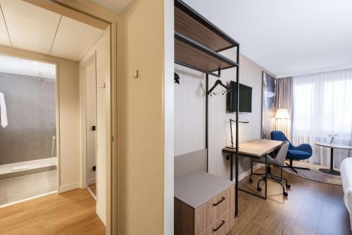 a room with a desk and a room with a bedroom at NH München Airport in Oberding