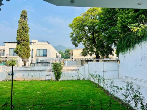 a fence in front of a house with a yard at Comfort Family Lodges in Islamabad