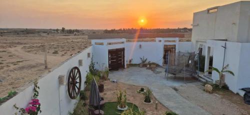 a white building with a sunset in the background at Dar Dalloula maison de vacances espace detente in Shanīnī