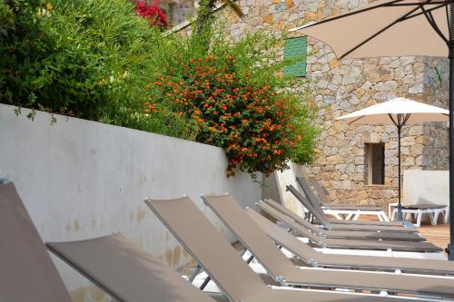 a row of lounge chairs with an umbrella and flowers at Residence Roc E Mare Cargèse in Cargèse