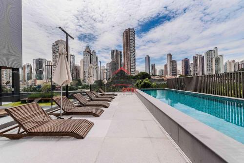 a swimming pool with chairs and a city skyline at Lumen in Sao Paulo