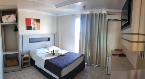 a small bedroom with a bed and a window at Hotel Joaçaba in Joaçaba