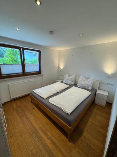 a bedroom with a bed with white sheets and two windows at Ferienwohnung Prutz Tullenweg 17 Oberinntal Tirol in Prutz