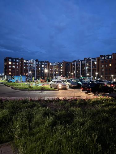 a parking lot with cars parked in front of buildings at Уютная новая квартира в ЖК Береке 2 рядом с Kostanay Plaza in Kostanay