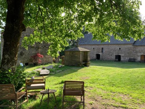 a group of chairs and a table in front of a building at Ancien Prieure Chambre King Size avec sauna et bain nordique privatifs en extérieur in Saint-Merd-les-Oussines
