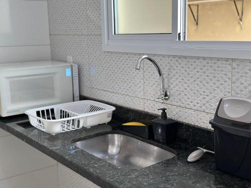 een aanrecht met een wastafel en een kraan bij Estadia no Caiçara com Praia a 150m! in Vila Balneária