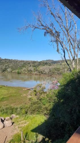 a view of a river with a tree in the foreground at Casa rústica às margens do lago in Maximiliano de Almeida