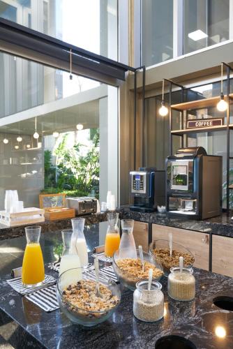a counter with three bowls of food and orange juice at Almarena Madero Urbano Affiliated by Melia in Buenos Aires