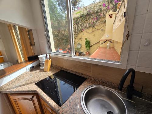 a kitchen counter with a sink and a window at nos appartements ciel et mer a tenerife in Puerto de la Cruz