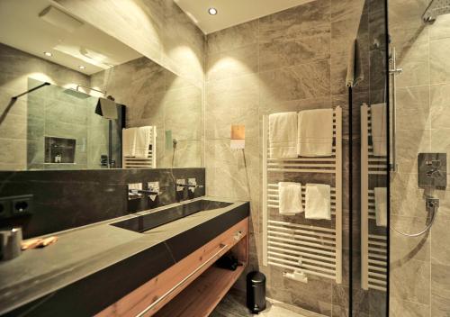 a bathroom with a sink and a shower with a mirror at Hotel Galtürerhof in Galtür
