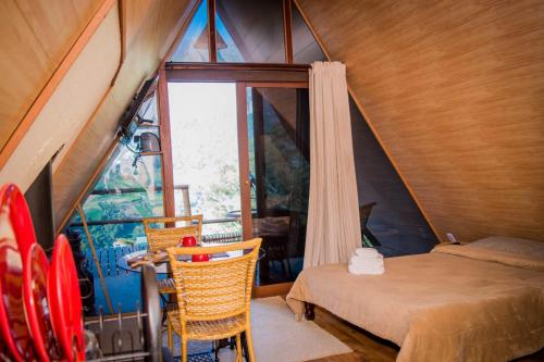 a bedroom with a bed and chairs and a window at Chalé Águia in Petrópolis