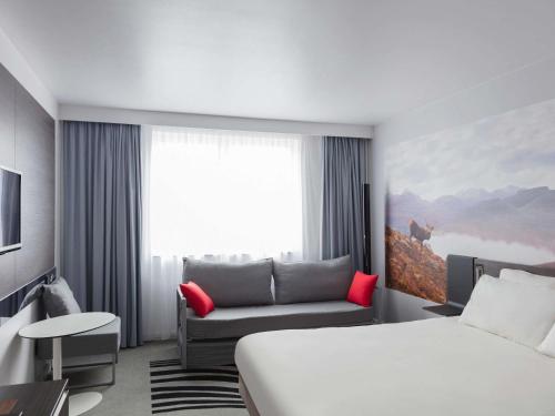 a hotel room with a bed and a couch at Novotel Edinburgh Centre in Edinburgh