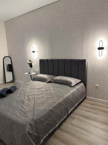 a bedroom with a large bed with a gray bedspread at Уютная новая квартира в ЖК Береке 2 рядом с Kostanay Plaza in Kostanay