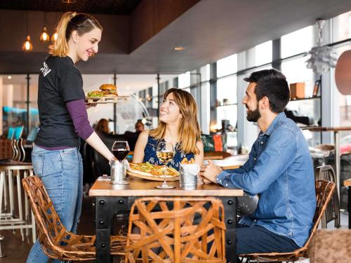 three people sitting at a table in a restaurant at Novotel Edinburgh Centre in Edinburgh