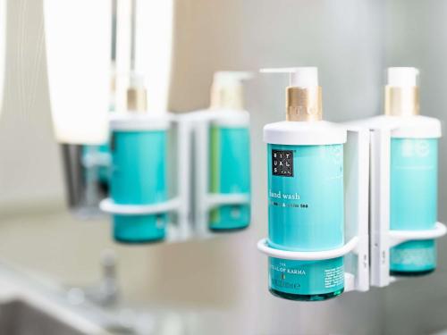 a row of blue bottles on a counter in a bathroom at Novotel Milton Keynes in Milton Keynes