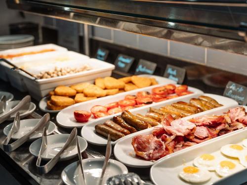 a buffet with plates of food on a table at Novotel Milton Keynes in Milton Keynes