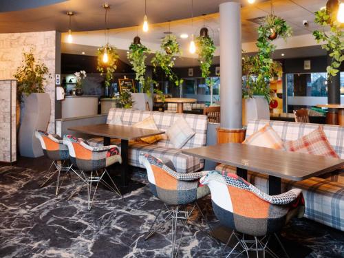 a restaurant with two tables and chairs and plants at Novotel Milton Keynes in Milton Keynes