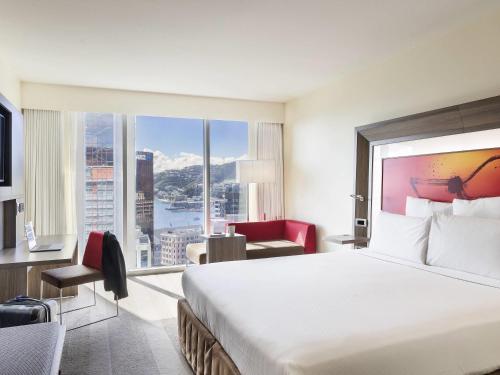 a hotel room with a large bed and a large window at Novotel Wellington in Wellington