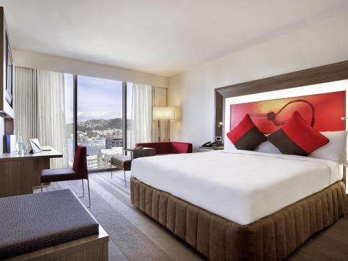 a hotel room with a large bed and a large window at Novotel Wellington in Wellington