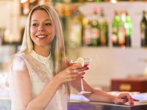 a woman is smiling while holding a glass of wine at Novotel Wellington in Wellington