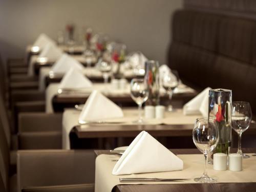 a row of tables with wine glasses and napkins at Novotel Düsseldorf City West in Düsseldorf