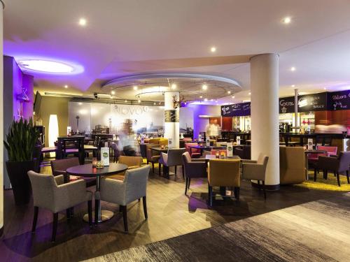 a restaurant with tables and chairs and purple lighting at Novotel Düsseldorf City West in Düsseldorf