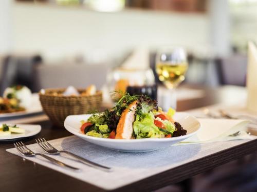a plate of food on a table with a glass of wine at Novotel Düsseldorf City West in Düsseldorf