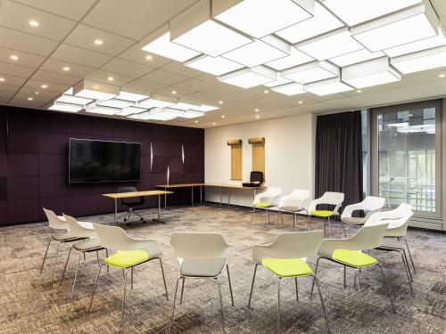 a conference room with white chairs and a flat screen tv at Novotel Düsseldorf City West in Düsseldorf