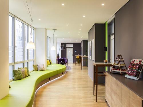 a living room with a green couch at Novotel Düsseldorf City West in Düsseldorf