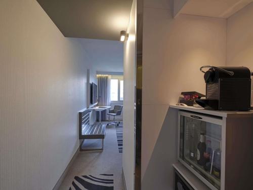 a room with a hallway with a television and a table at Novotel München City in Munich