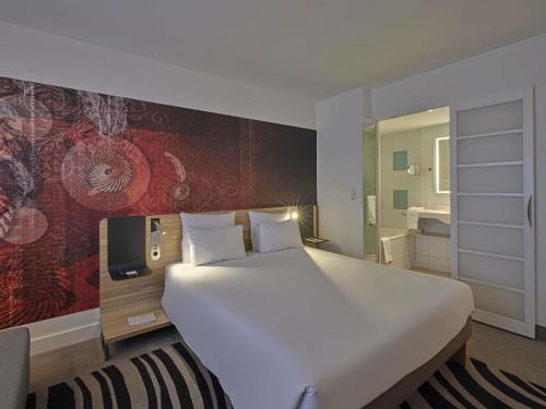 a bedroom with a large white bed and a wall mural at Novotel München City in Munich