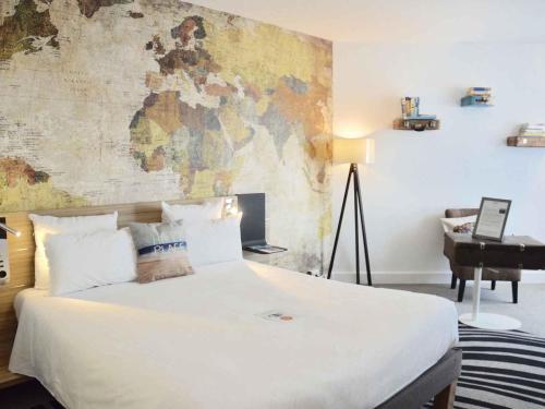 a bedroom with a large white bed with a map on the wall at Novotel München City in Munich