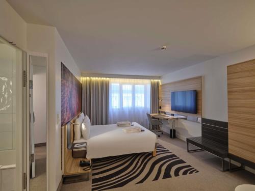a hotel room with a bed and a desk at Novotel München City in Munich