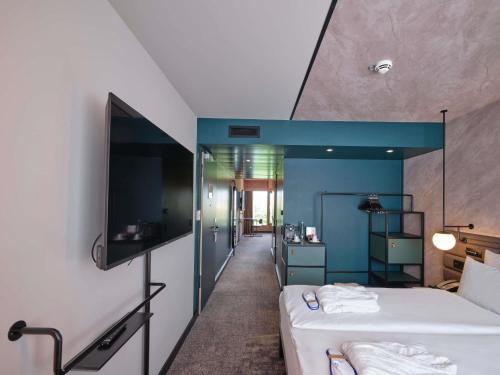 a hotel room with a bed and a tv at Novotel München City in Munich