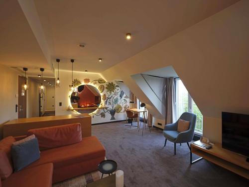 a living room with a couch and chairs and a tv at Novotel München City in Munich