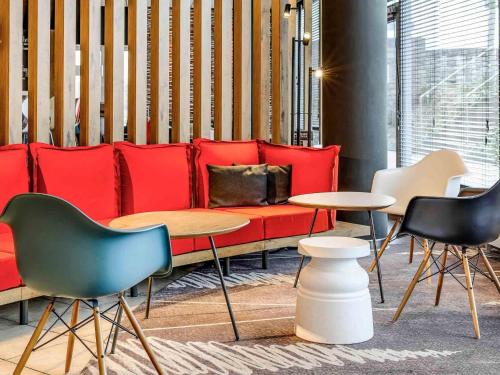 a room with a red couch and chairs and tables at ibis Hotel Würzburg City in Würzburg