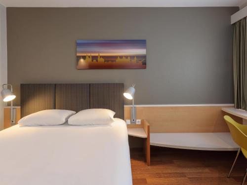 a hotel room with a bed and a desk and a tv at ibis Hotel Würzburg City in Würzburg