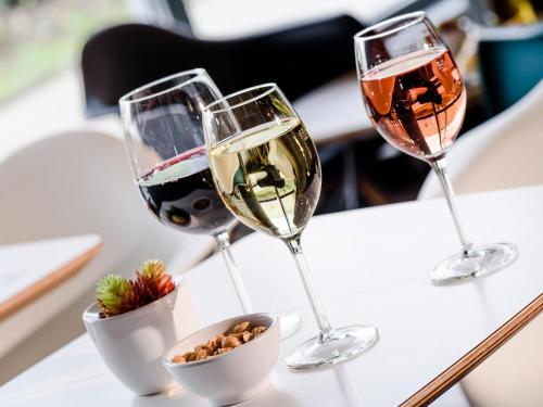 three glasses of white wine and a bowl of nuts at ibis Hotel Würzburg City in Würzburg