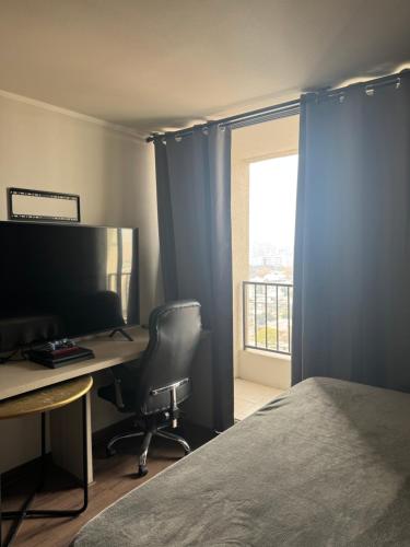 a bedroom with a desk and a bed and a window at Amplio Apartaestudio in Santiago