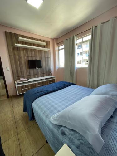 a bedroom with a bed with a blue blanket and a television at Residencial Nicole in Florianópolis
