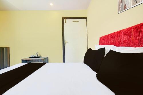 a bedroom with a white bed and a red headboard at Hotel O Paradise Green in Indore