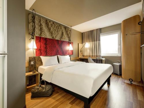 a bedroom with a large white bed and a window at ibis Hotel München Messe in Feldkirchen
