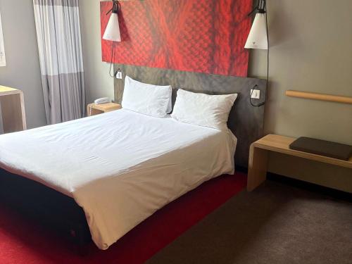 a bedroom with a large bed with white sheets and pillows at ibis Paris La Defense Courbevoie in Courbevoie